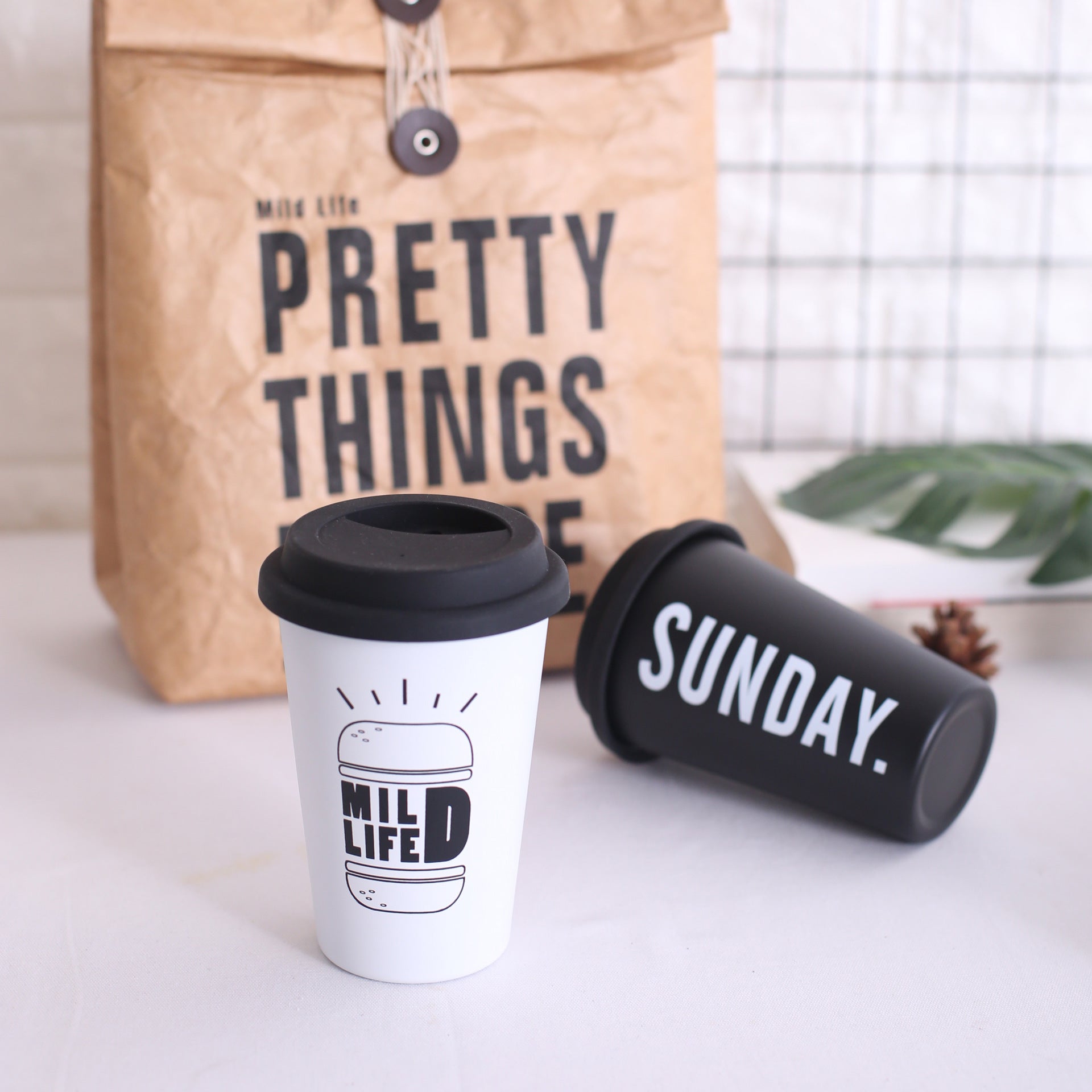 Two coffee cups with 'Mild Life' and 'Sunday' text, a brown bag with 'Pretty Things' text in the background.