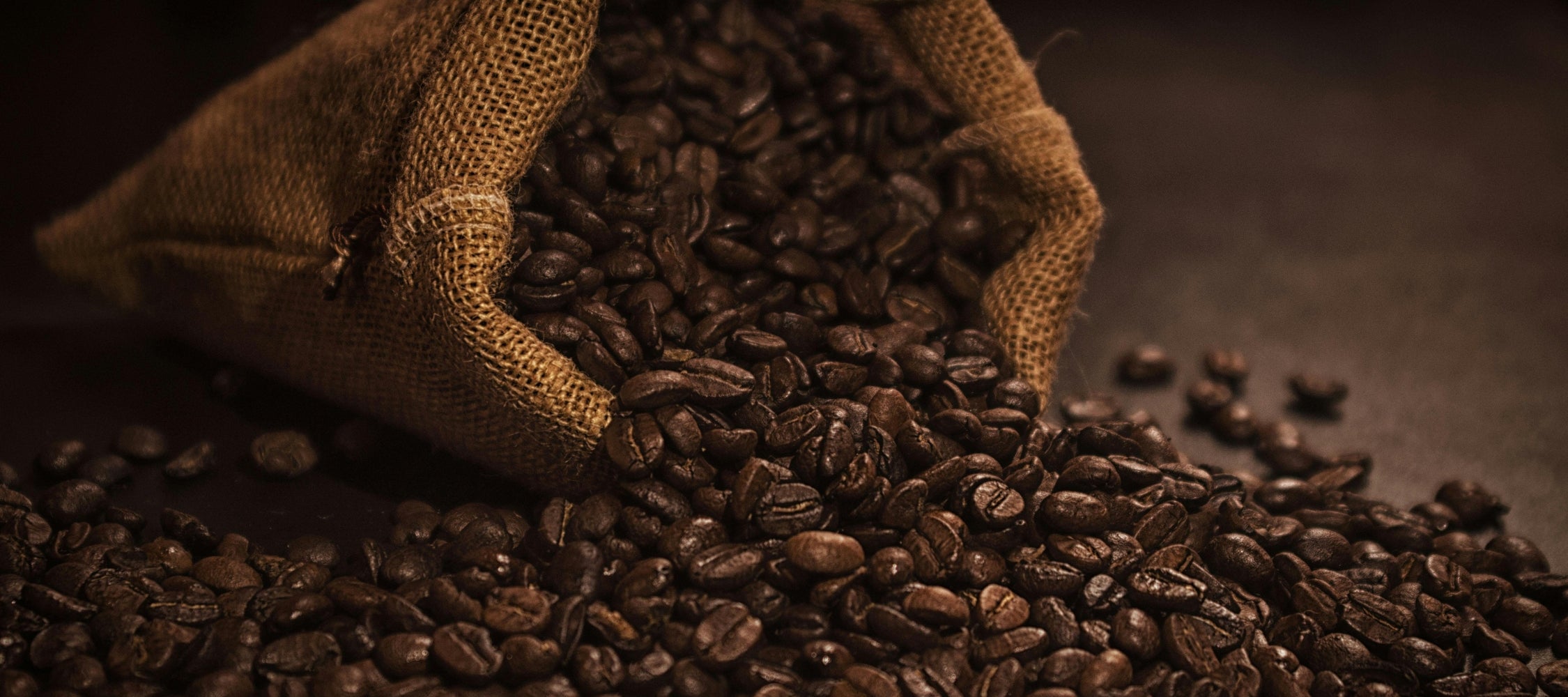 Sack of coffee beans spilling out on a dark background