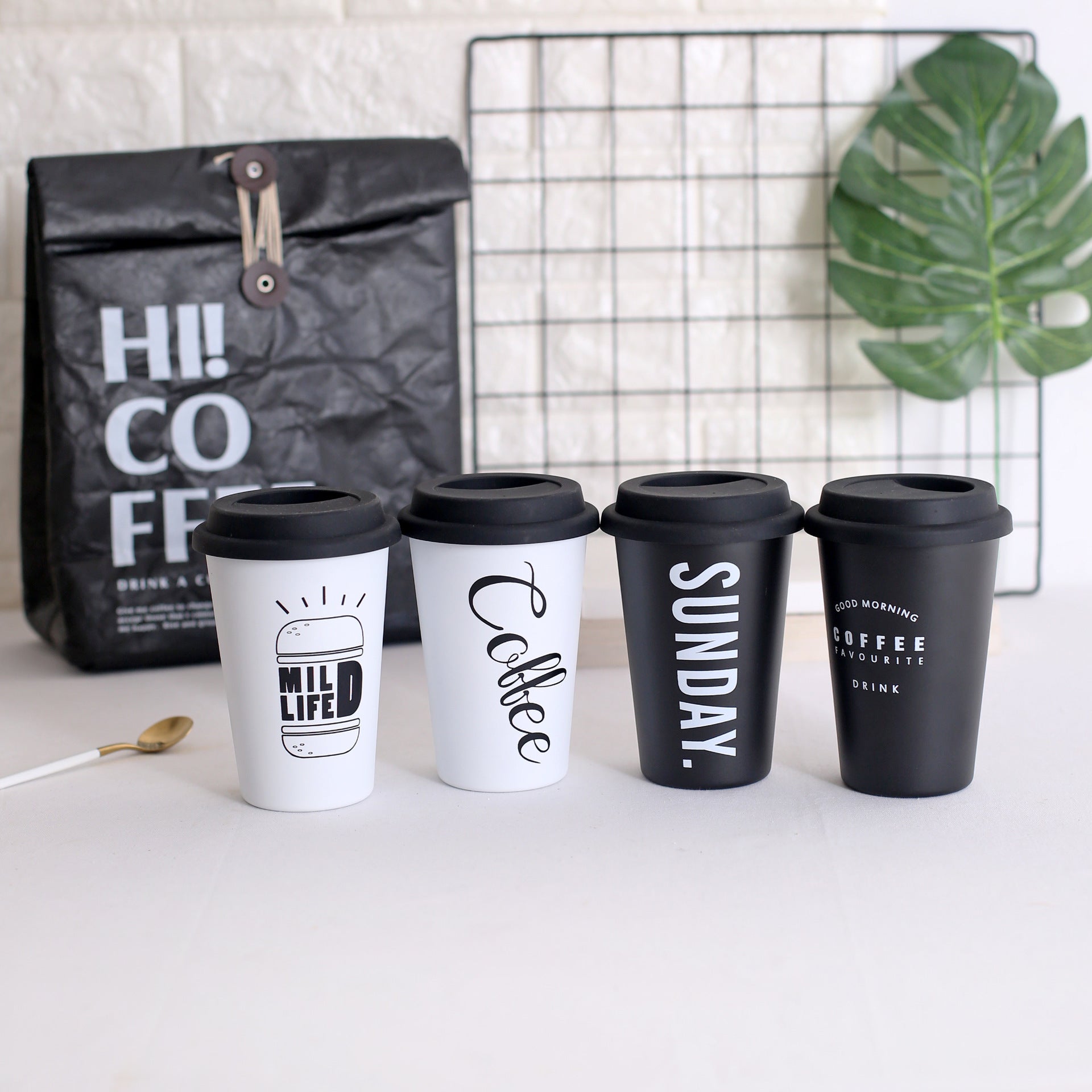 Set of coffee cups with text designs on a white surface, with a coffee bag in the background.