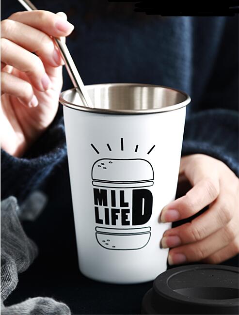 Person holding a white tumbler with 'Mild Life' design and straw, wearing a dark blue sweater.